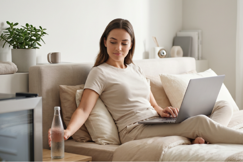 Chilled water bottle on nightstand next to a laptop user.